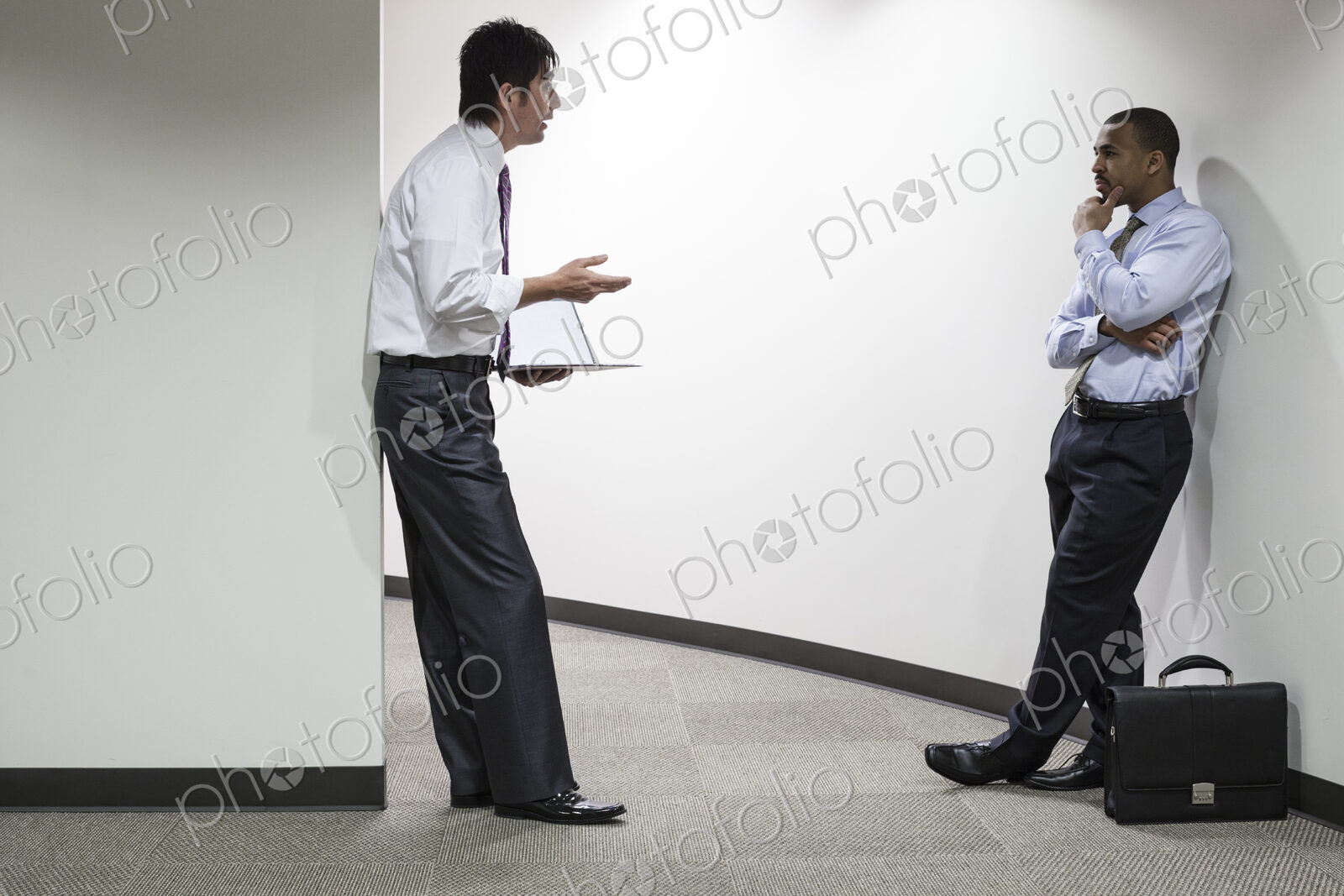 An asian businessman and a black businessman talking over an issue in an office