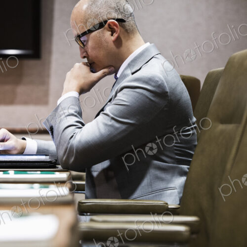 An asian businessman sitting at a conference table working on a notebook computer,… An asian businessman sitting at a conference table working on a notebook computer,…