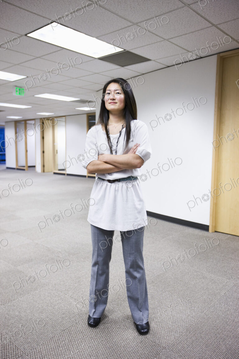 An asian businesswoman stanidng alone in her office space.