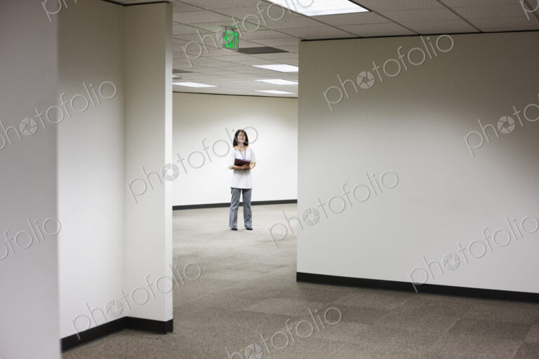 An asian businesswoman stanidng alone in her office space.