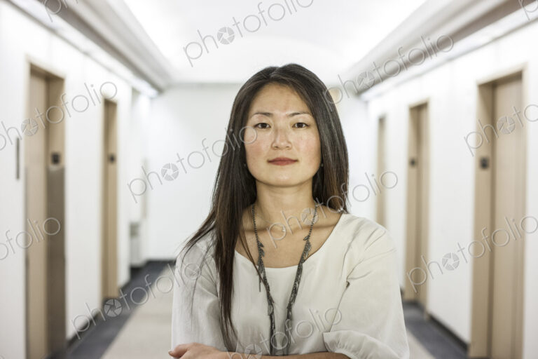 An asian businesswoman stanidng alone in her office space.