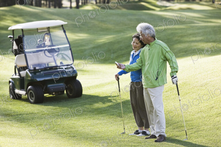 An asian senior couple checking the yards to the flag for the next shot.