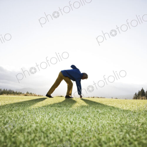 An asian senior man teeing up a golf ball and ready to swing.