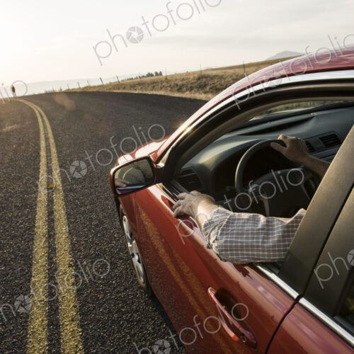 An automobile approaching a person standing on the side of a road. An automobile approaching a person standing on the side of a road.