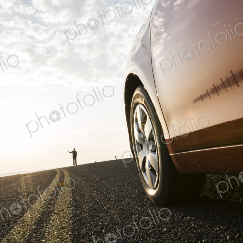 An automobile approaching a person standing on the side of a road. An automobile approaching a person standing on the side of a road.