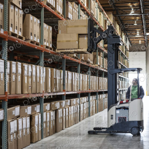 An employee picking products off a rack using a forklift stock picker in a… An employee picking products off a rack using a forklift stock picker in a…