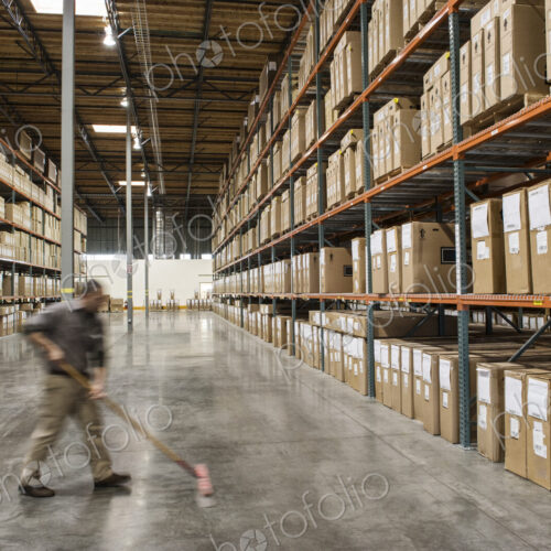 An employee sweeping the floor of a distribution warehouse. An employee sweeping the floor of a distribution warehouse.