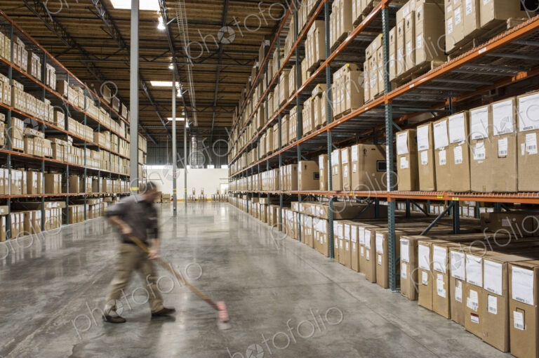 An employee sweeping the floor of a distribution warehouse.
