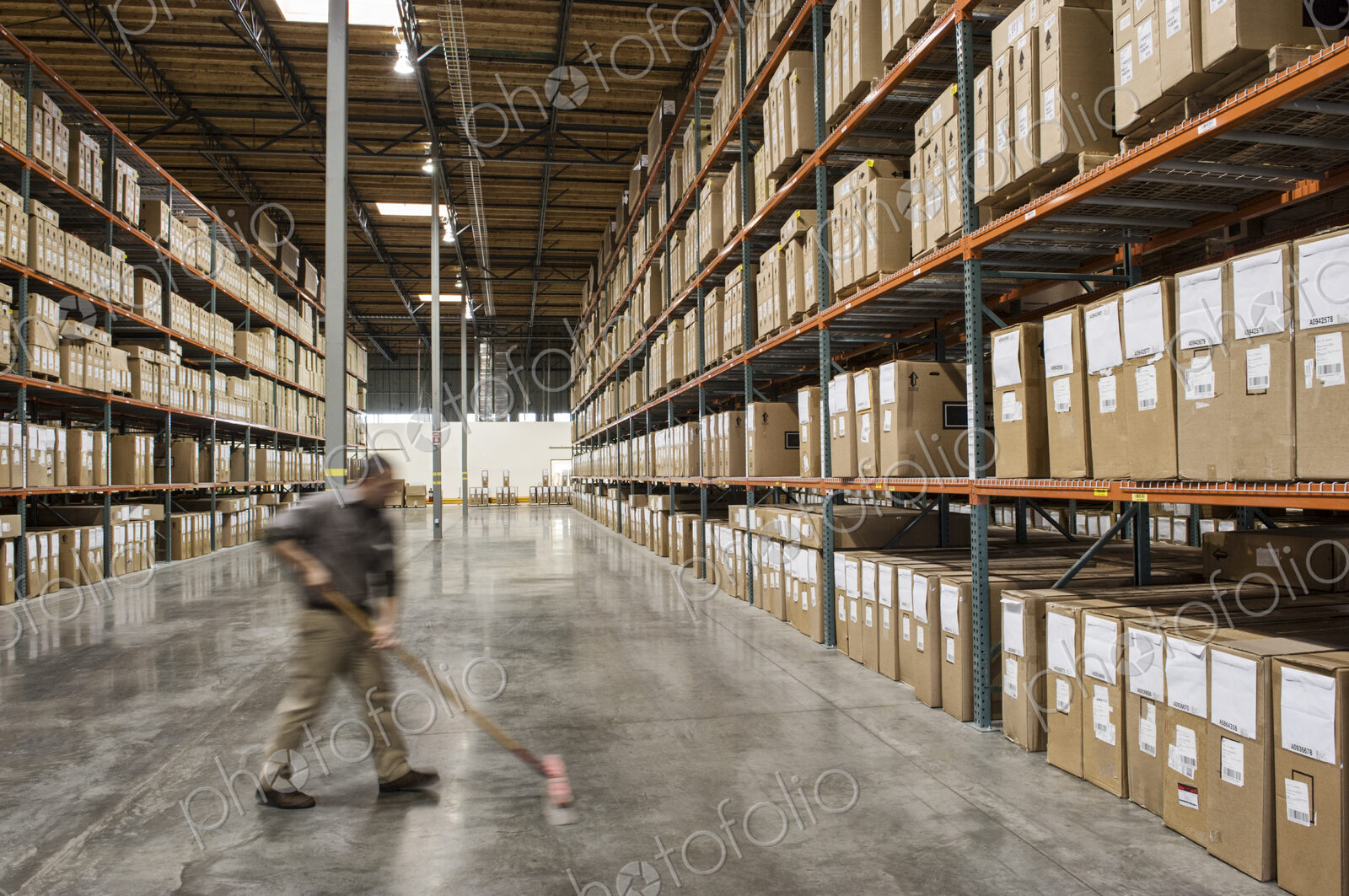 An employee sweeping the floor of a distribution warehouse.
