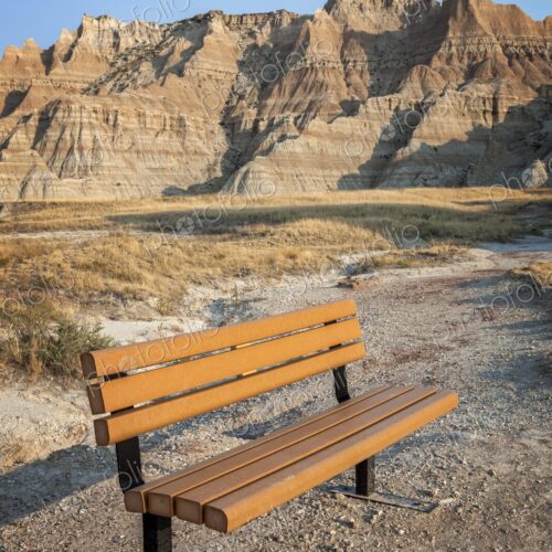 An empty bench faces the layered buttes of Badlands National Park, South Dakota, at…