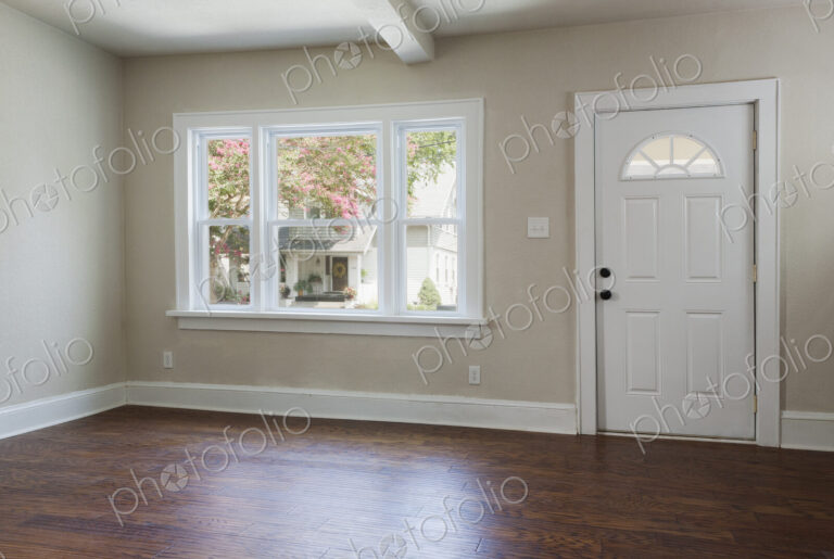 An empty entrance hall with hardwood floors and front door entrance.