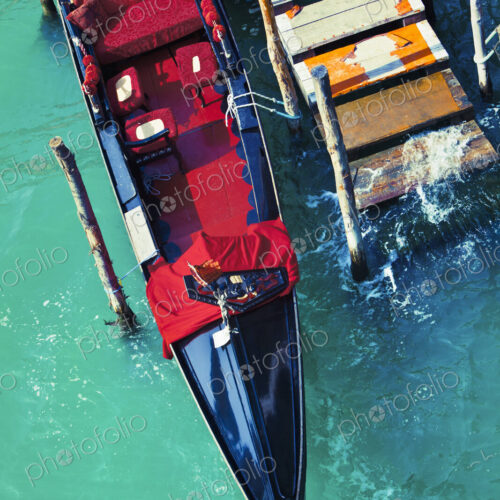 An empty gondola docked at a worn out pier in the city of Venice, Italy.