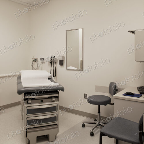 An examination room in a hospital, with a treatment table, patient bed, a stool and chair. An examination room in a hospital, with a treatment table, patient bed, a stool and chair.
