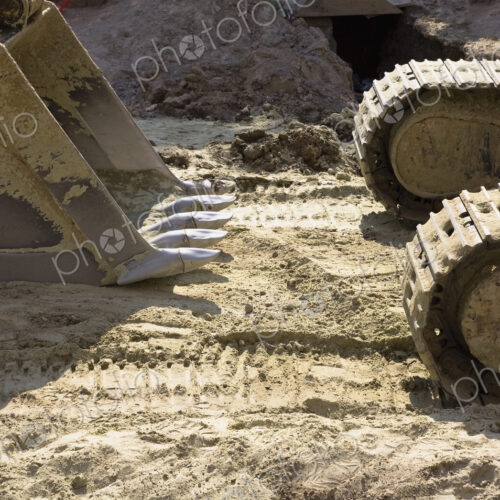 An excavator with caterpillar tracks and a large scoop bucket on a construction site.