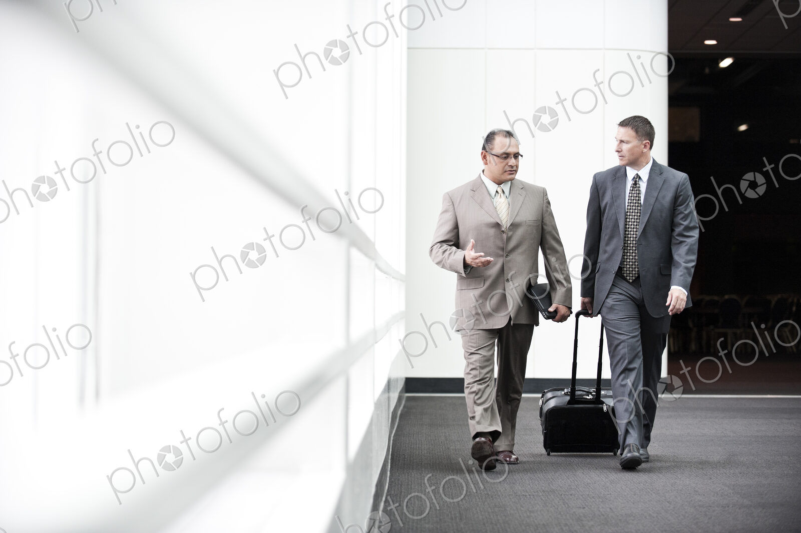 An hispanic businessman and a caucasian businessman walking and talking together in a…