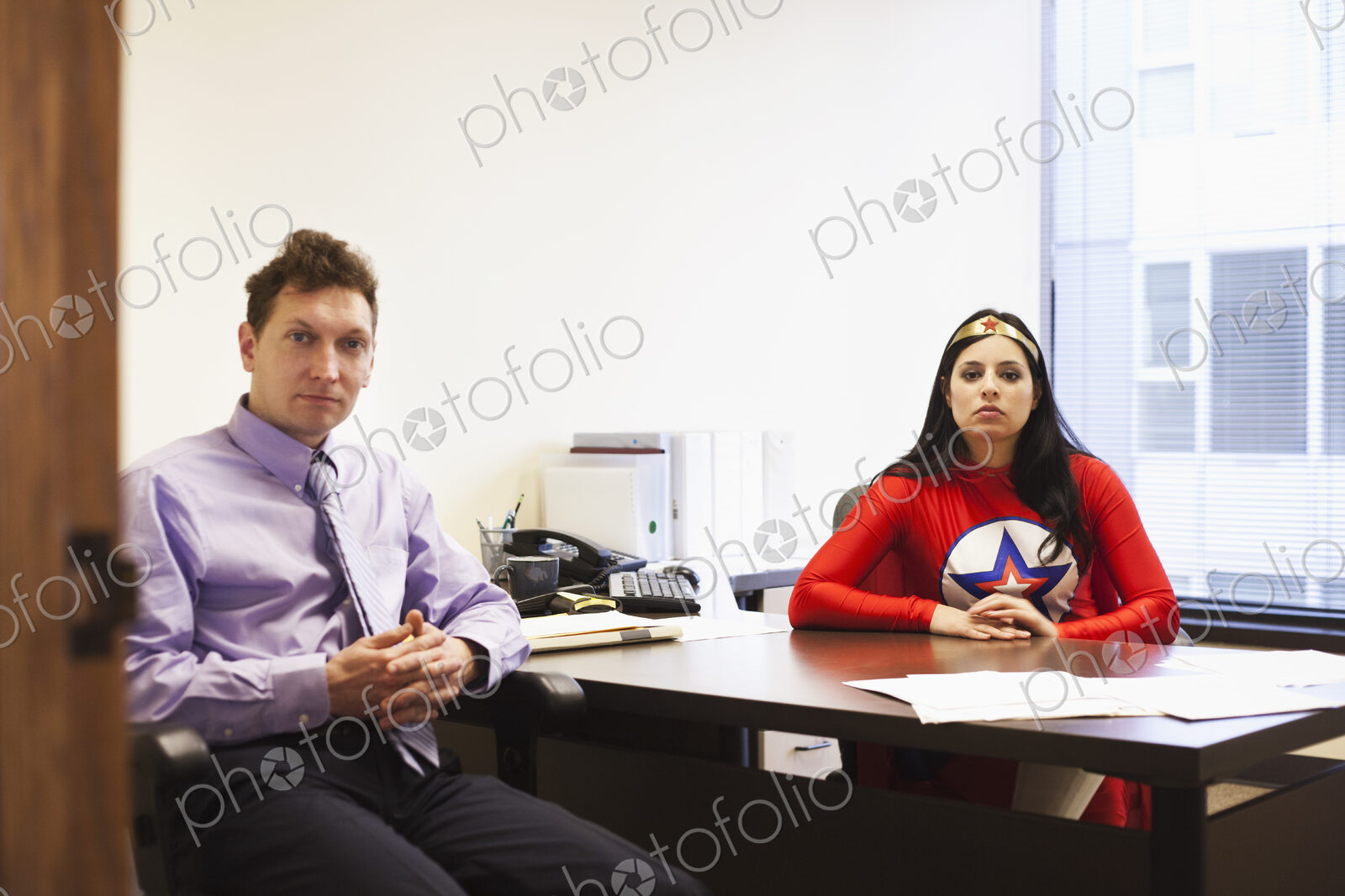 An hispanic businesswoman office super hero and her caucasian male team member in her…