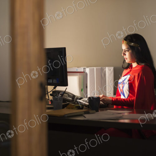 An hispanic businesswoman office super hero at her office computer An hispanic businesswoman office super hero at her office computer