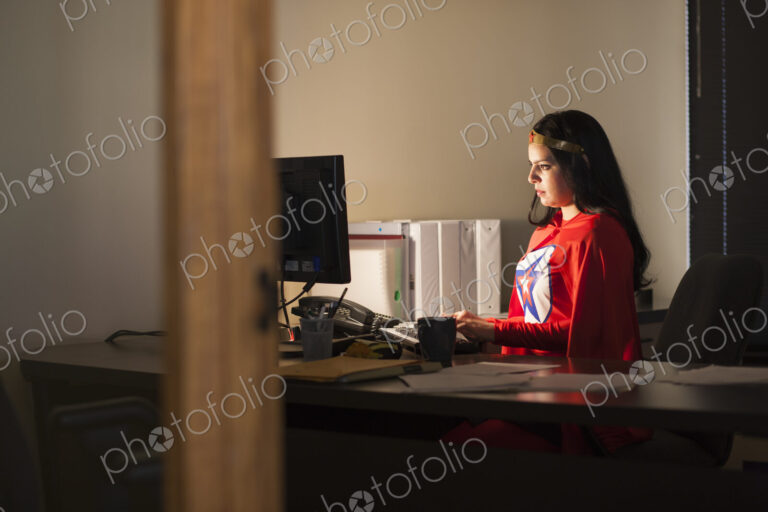 An hispanic businesswoman office super hero at her office computer