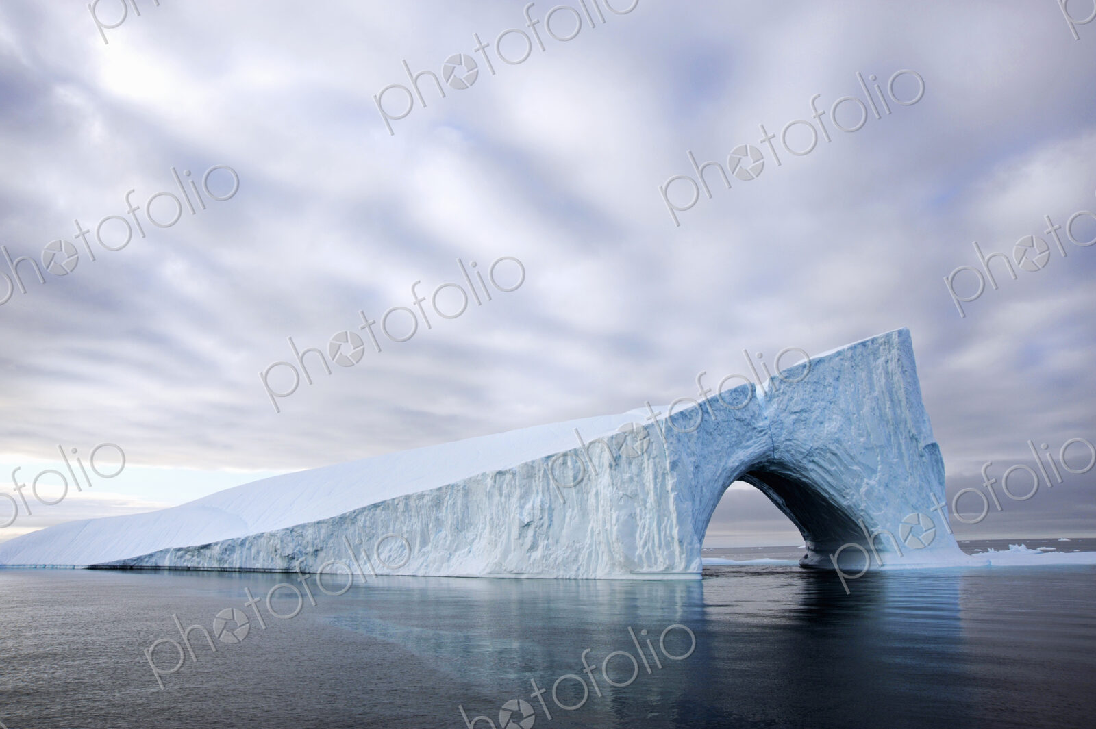 An iceberg on the water of Baffin Bay, with a natural arch.