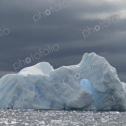 An iceberg on the waters of the Southern Ocean under a stormy grey sky. An iceberg on the waters of the Southern Ocean under a stormy grey sky.