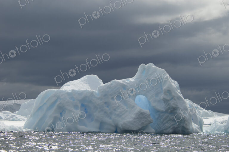 An iceberg on the waters of the Southern Ocean under a stormy grey sky.