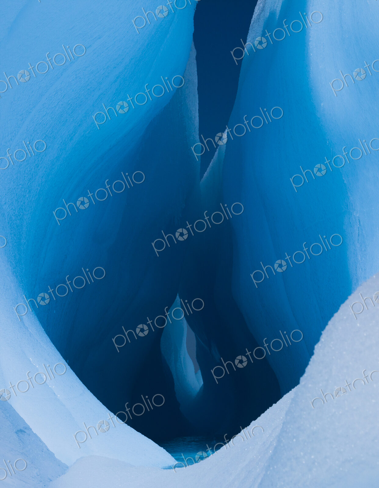 An iceberg with a deep crevasse or fissure, and the contours of melting ice, in…