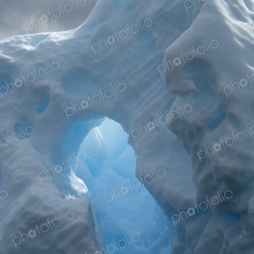 An iceberg with a natural arch and translucent glow, with sunlight shining through the… An iceberg with a natural arch and translucent glow, with sunlight shining through the…