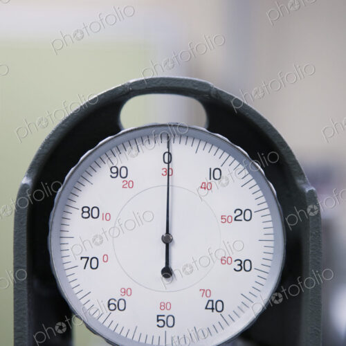An industrial gauge in a factory, dial with numbers.