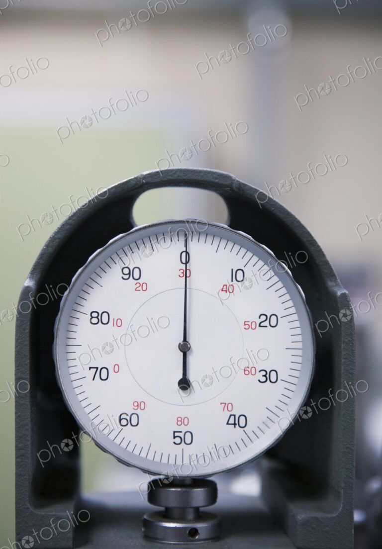 An industrial gauge in a factory, dial with numbers.