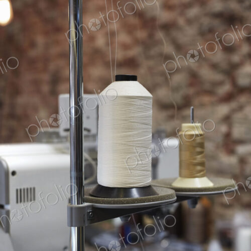 An industtrial sewing machine in a leather workshop, with a bare brick wall in the… An industtrial sewing machine in a leather workshop, with a bare brick wall in the…