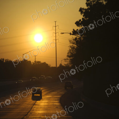 An interstate highway, road bordered by trees, a car driving into the sunset. An interstate highway, road bordered by trees, a car driving into the sunset.