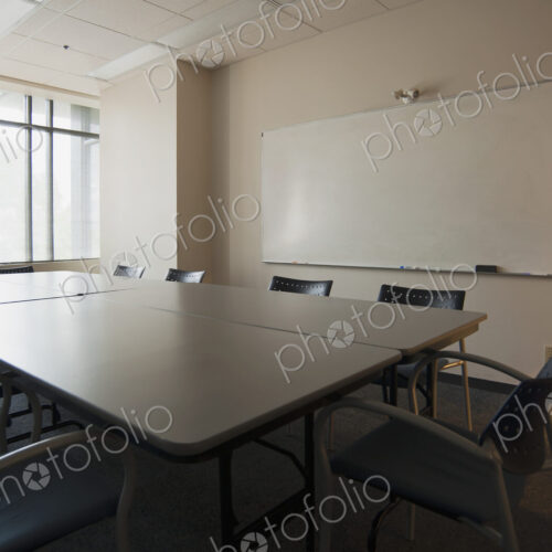 An office boardroom with table and chairs and a whiteboard on the wall.