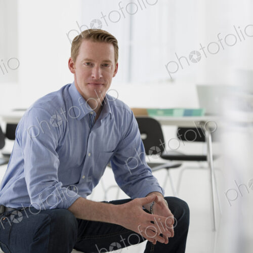 An office in the city. Business. A man in a blue shirt sitting down.