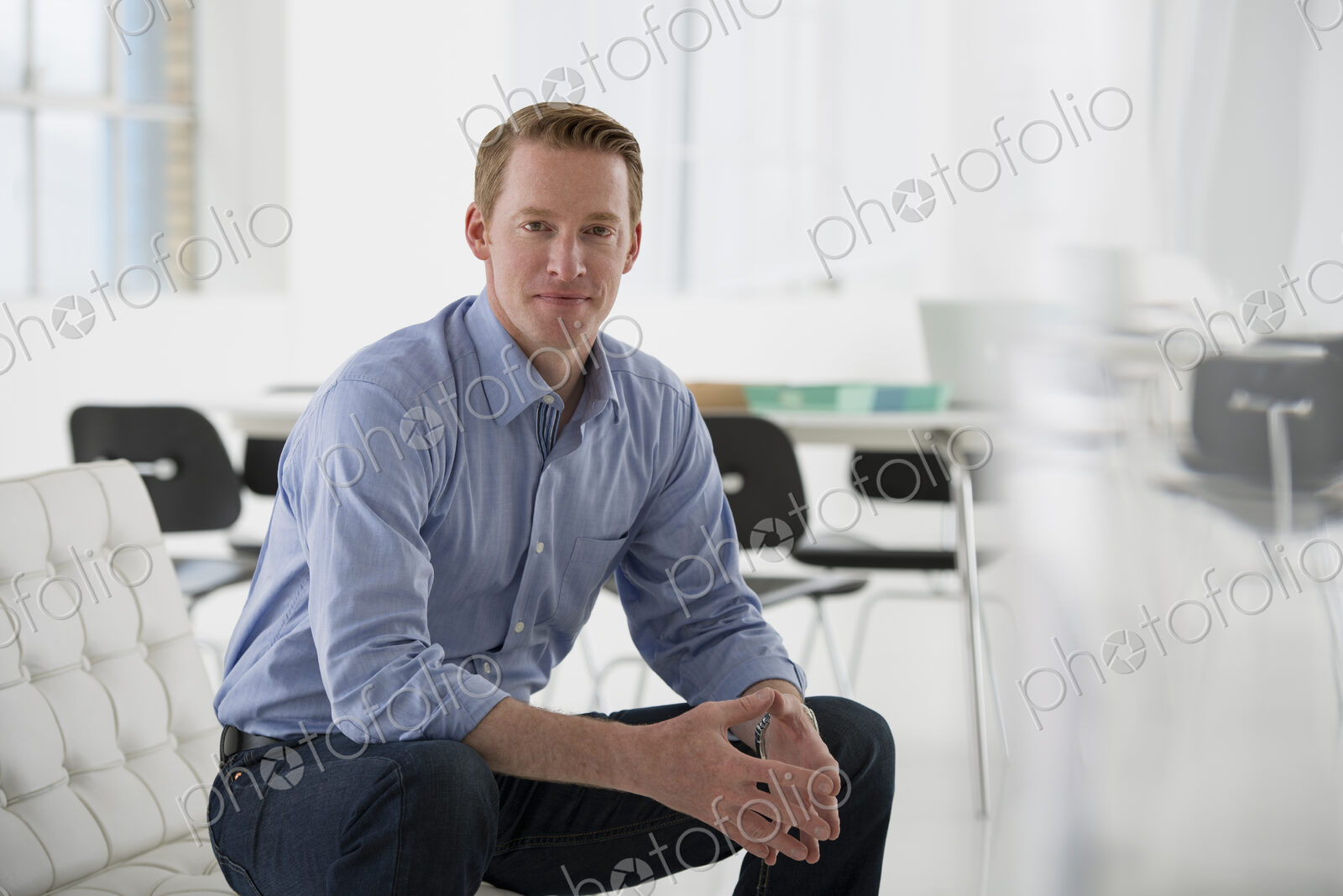 An office in the city. Business. A man in a blue shirt sitting down.