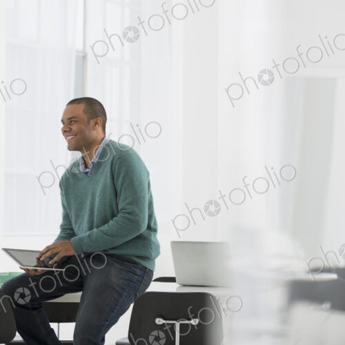 An office in the city. Business. A man leaning on a desk holidn ga digital tablet. An office in the city. Business. A man leaning on a desk holidn ga digital tablet.