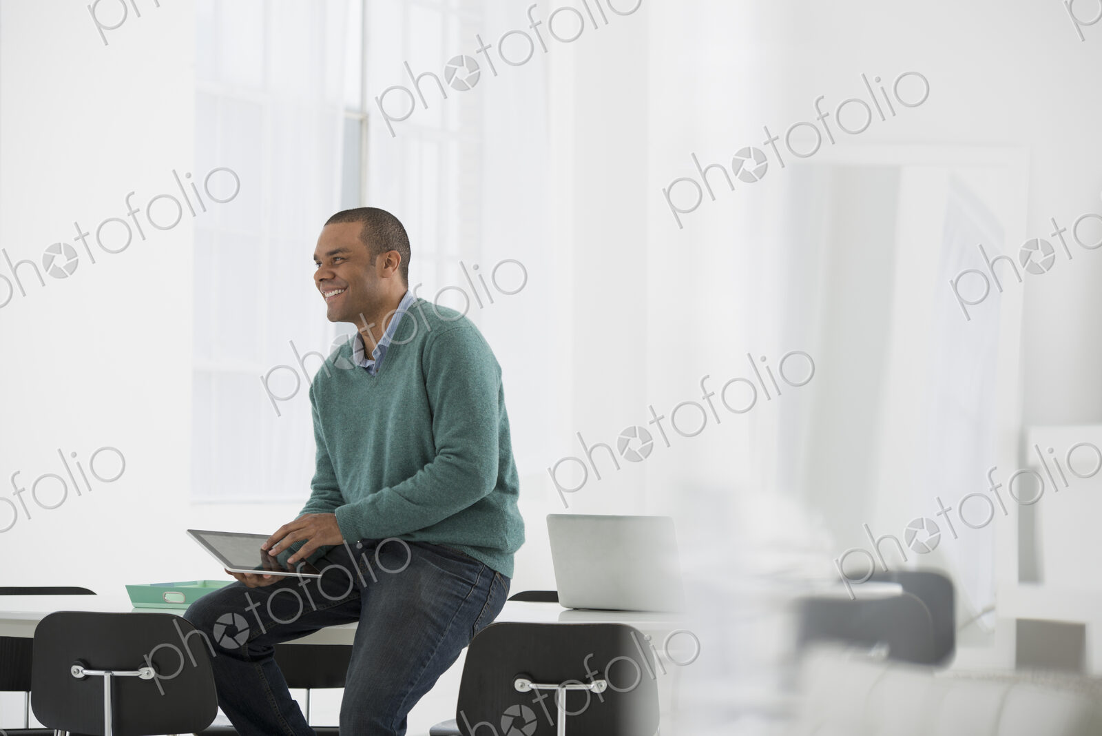 An office in the city. Business. A man leaning on a desk holidn ga digital tablet.