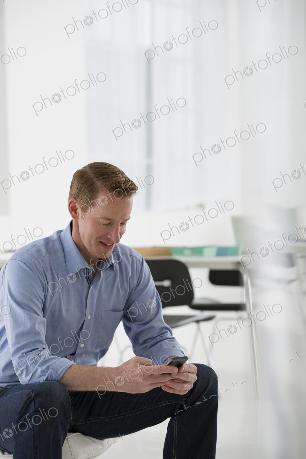 An office in the city. Business. A man seated, checking his smart phone for messages…