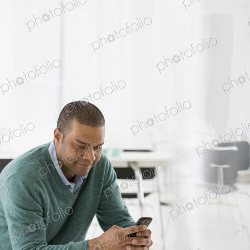 An office in the city. Business. A man seated, checking his smart phone for messages… An office in the city. Business. A man seated, checking his smart phone for messages…
