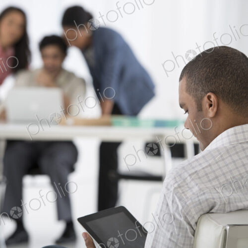An office in the city. Business. A man seated in the foreground, and three people…