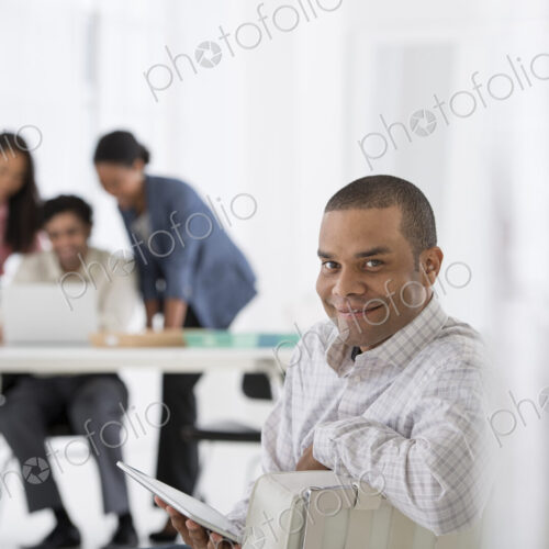 An office in the city. Business. A man seated in the foreground, and three people…