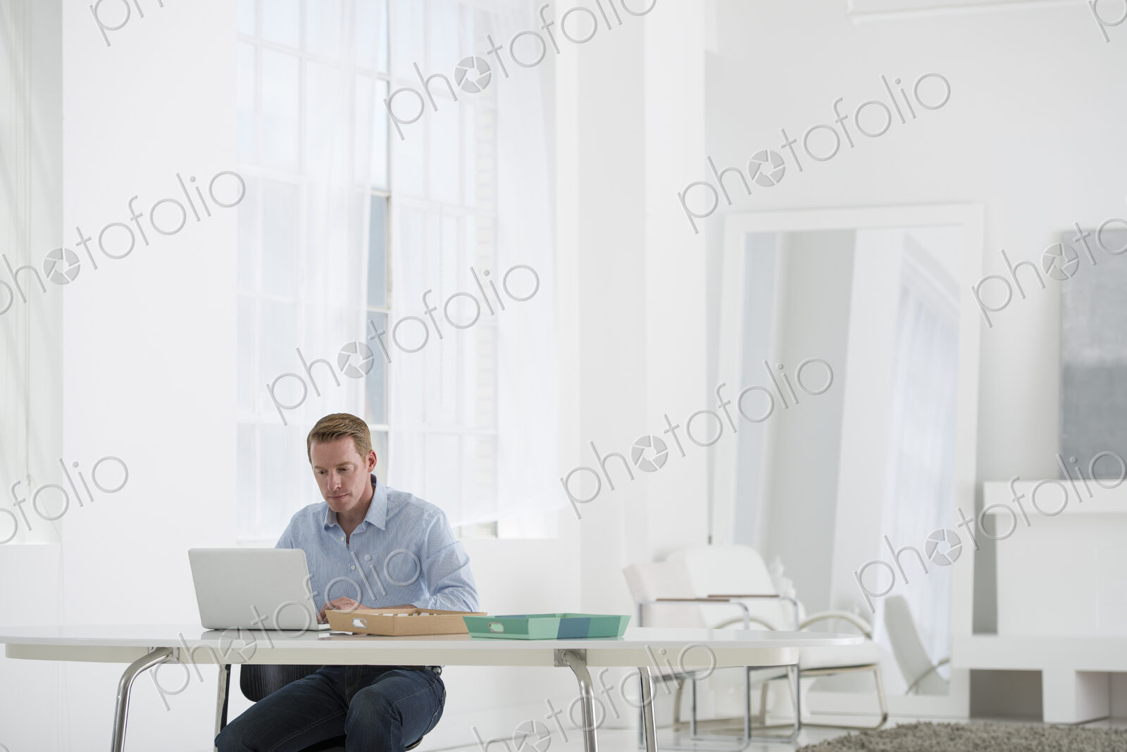 An office in the city. Business. A man sitting at a desk using a laptop.