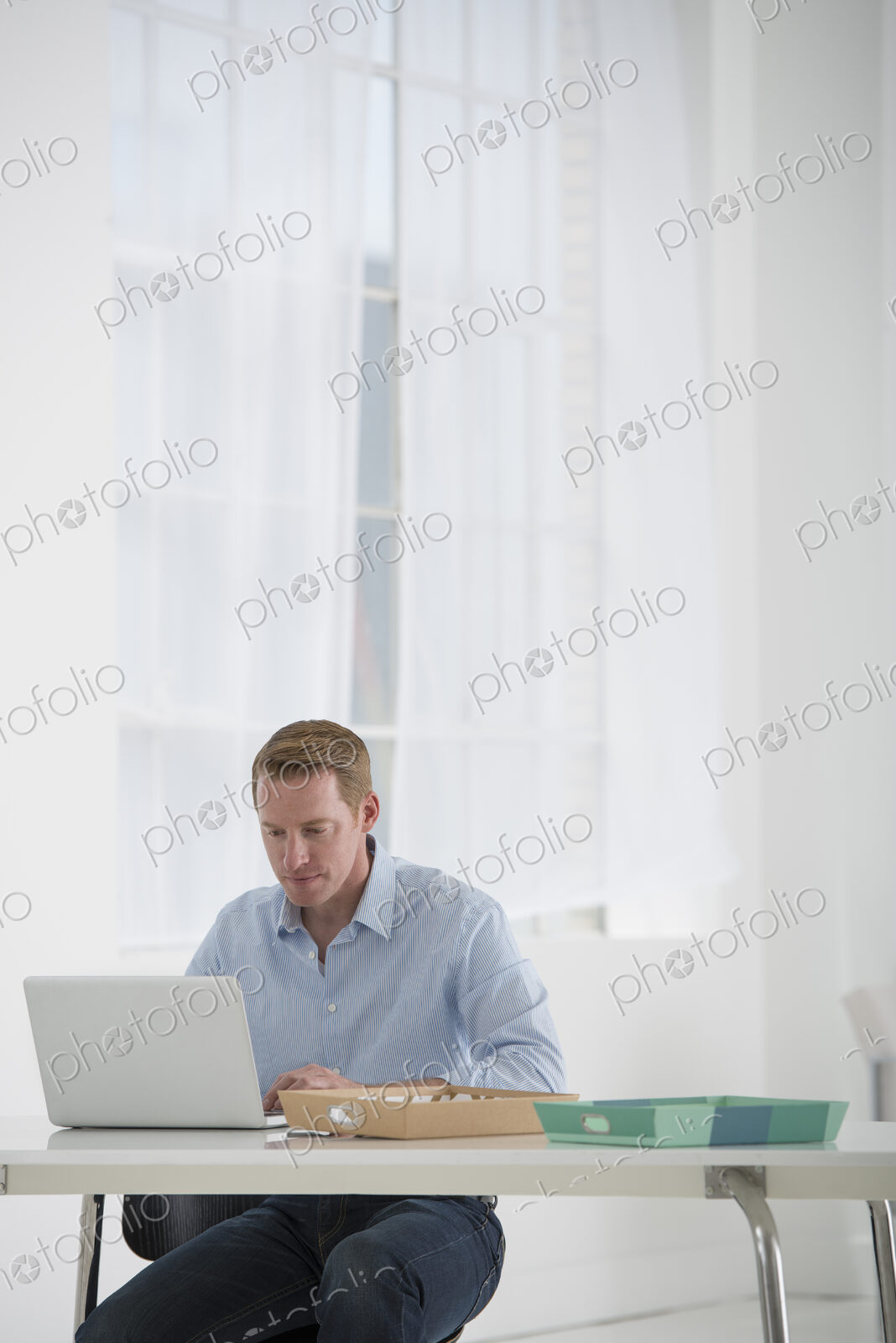 An office in the city. Business. A man sitting at a desk using a laptop.
