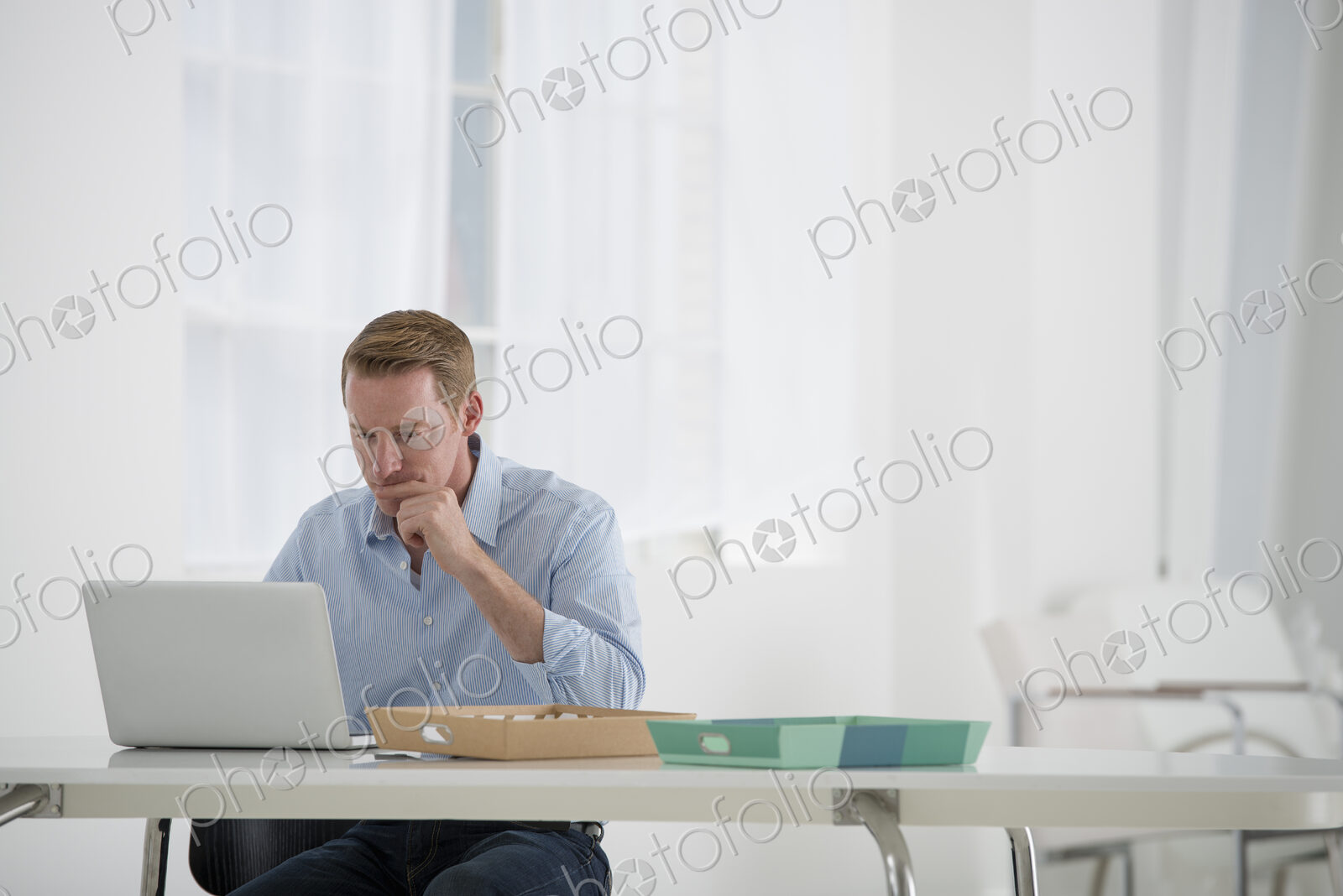 An office in the city. Business. A man sitting at a desk using a laptop.