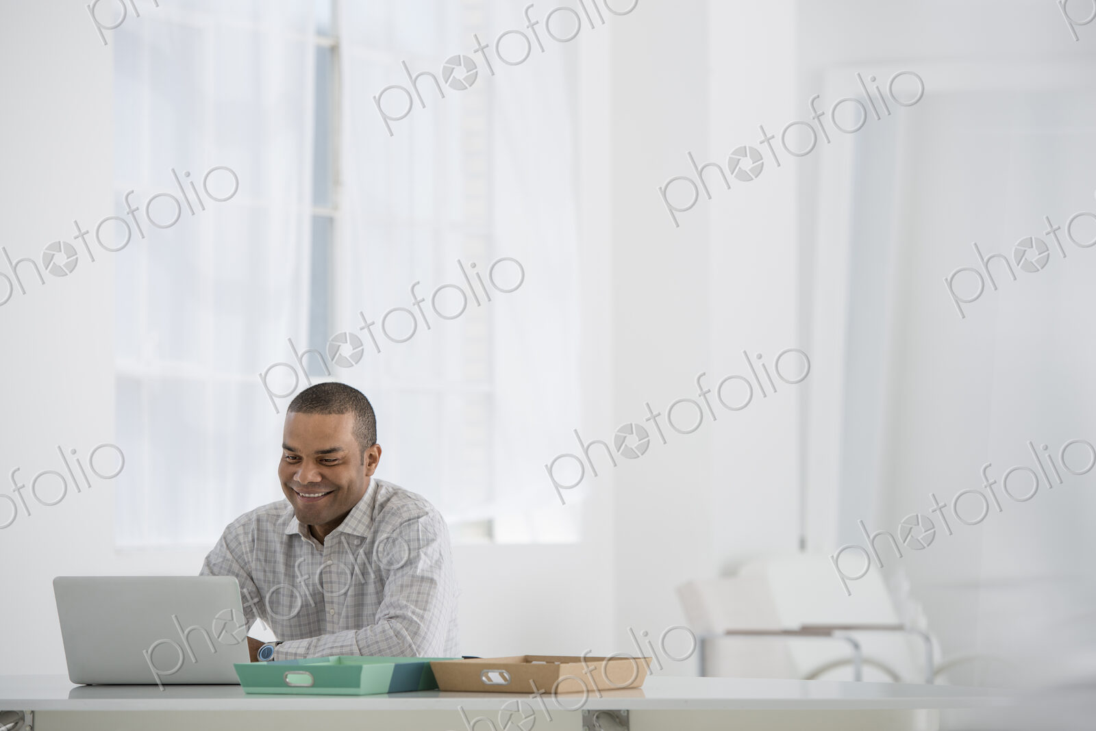An office in the city. Business. A man sitting at a desk using a laptop.