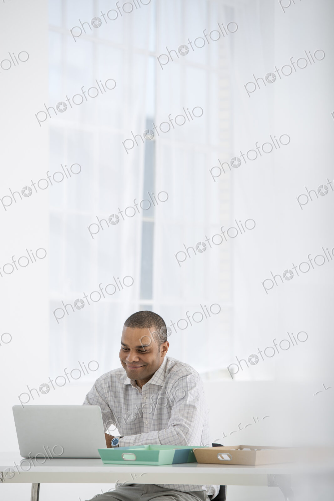 An office in the city. Business. A man sitting at a desk using a laptop.