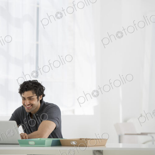 An office in the city. Business. A man sitting at a desk using a laptop.