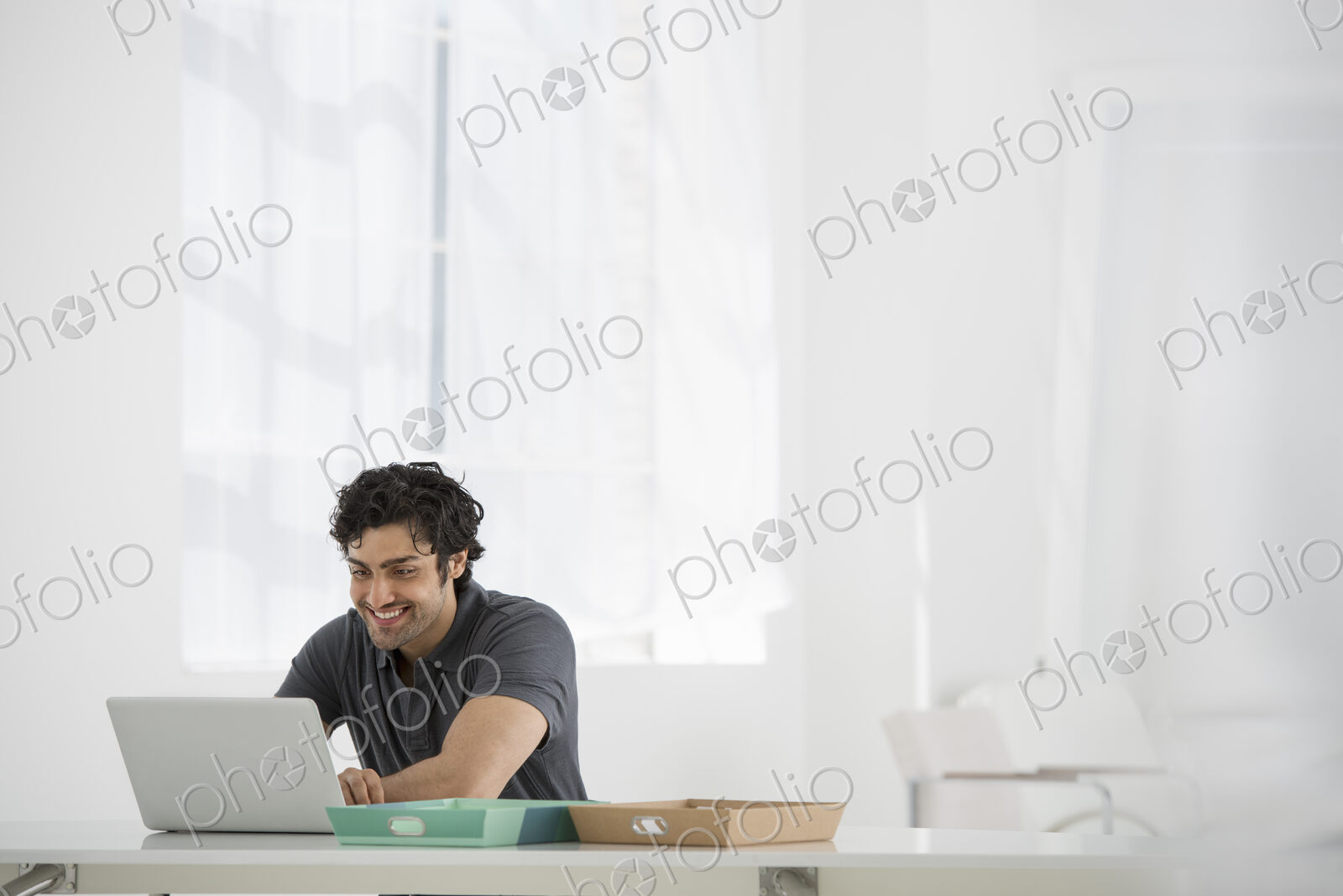 An office in the city. Business. A man sitting at a desk using a laptop.