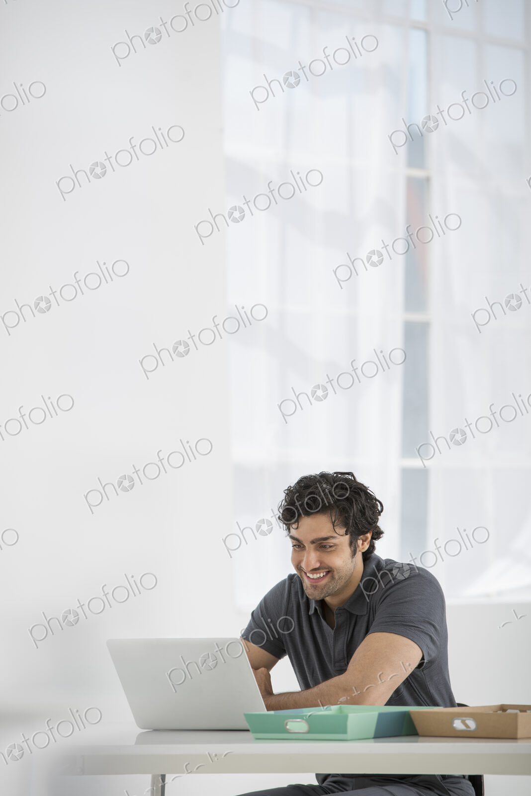 An office in the city. Business. A man sitting at a desk using a laptop.