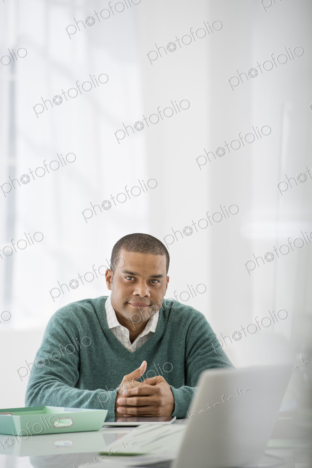 An office in the city. Business. A man sitting with his hands clasped behind a desk.