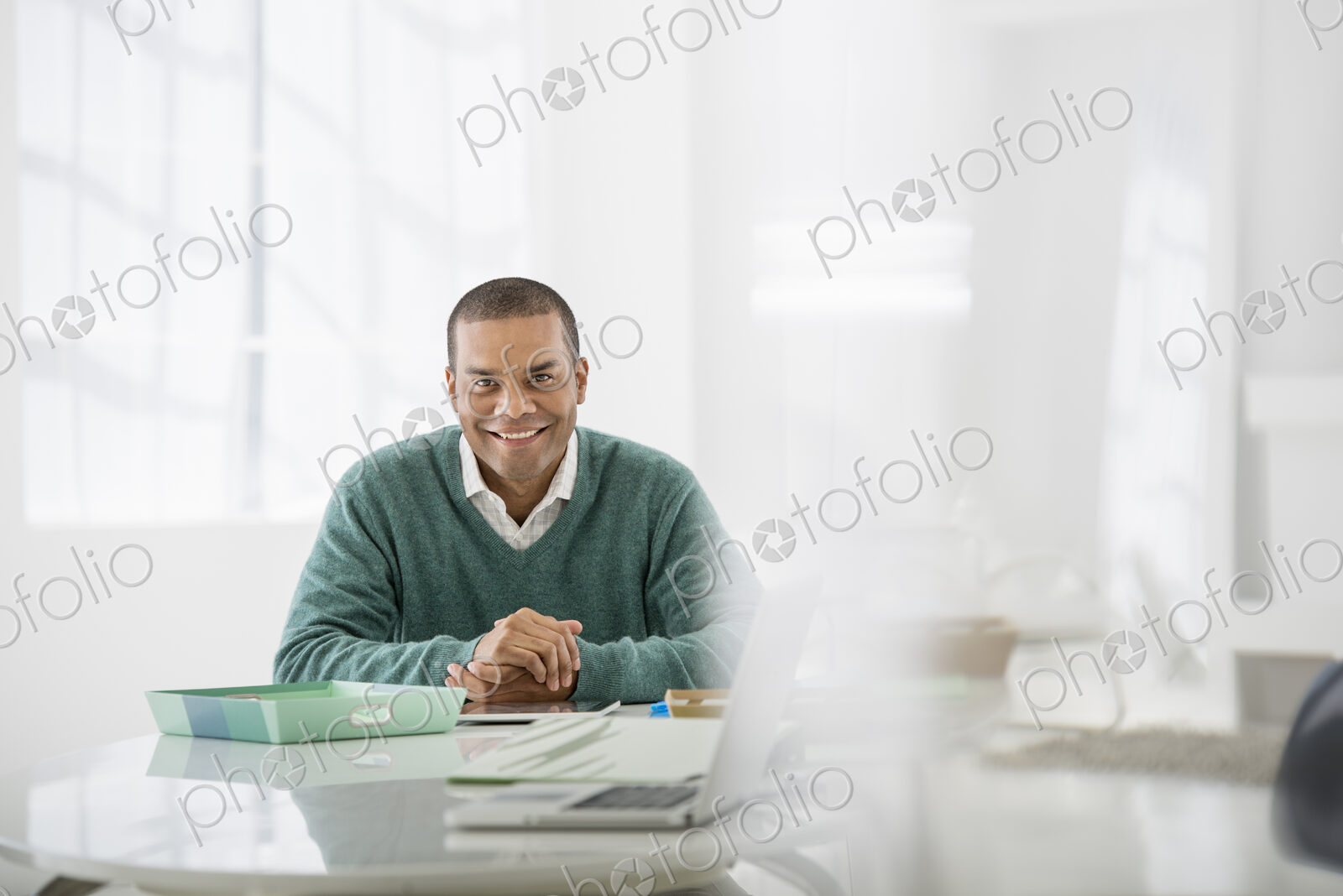An office in the city. Business. A man sitting with his hands clasped behind a desk.